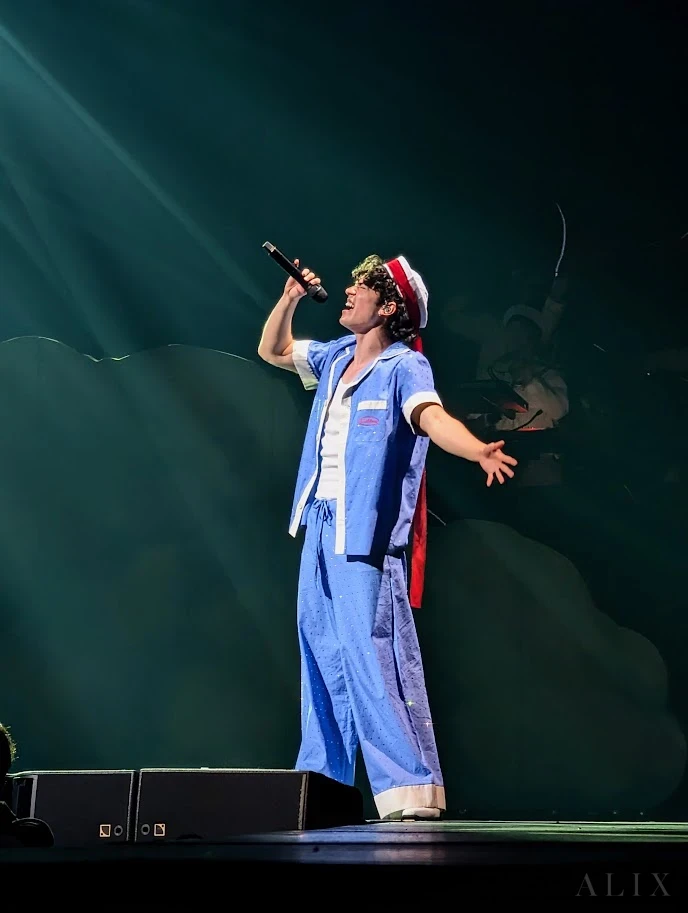 A singer in a blue shirt and cap holding a microphone during a live performance.